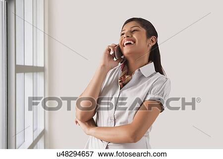Stock Photo - Cheerful young business woman enjoying the conversation on phone call . Fotosearch