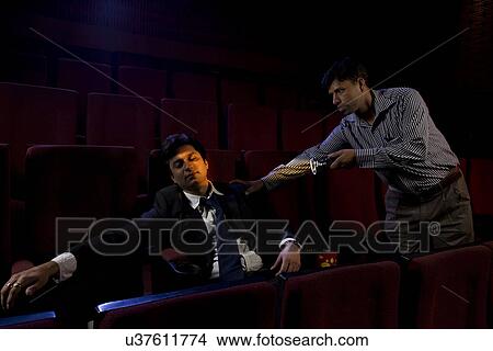 Picture - Cinema hall attendant waking a sleeping man . Fotosearch
