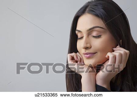 Close-up of a beautiful Indian young woman with eyes closed over colored background View Large Photo Image Stock Photography - Close-up of a beautiful Indian young woman with eyes closed over colored background . Fotosearch