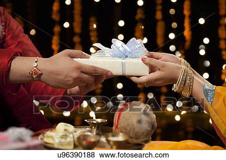 Stock Photo - Close-up of a man giving gift to his sister. Fotosearch