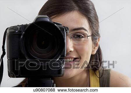 Stock Photo - Close-up of a smiling young woman taking a photograph . Fotosearch
