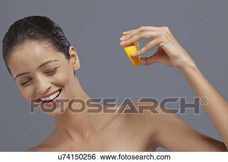 Close-up of a woman squeezing juice from orange on her face View Large Photo Image Stock Photograph - Close-up of a woman squeezing juice from orange on her face . Fotosearch