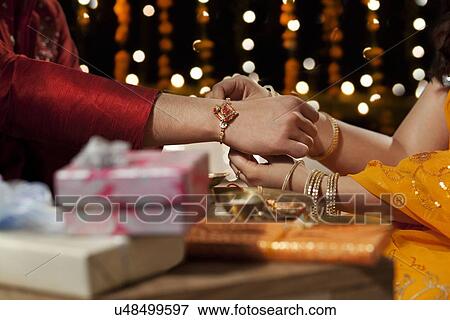 Close-up of a woman tying rakhi on her brother's hand View Large Photo Image Stock Photo - Close-up of a woman tying rakhi on her brother's hand. Fotosearch