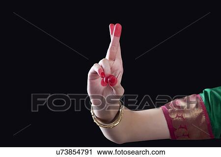 Stock Image - Close-up of a woman's hand making a Bharatanatyam gesture called Kartarimukha on black background. Fotosearch