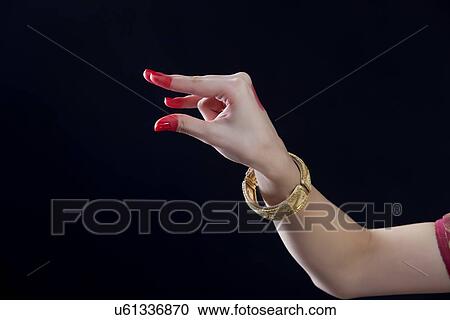 Stock Image - Close-up of a woman's hand making Bharatanatyam gesture called Kangula on black background. Fotosearch
