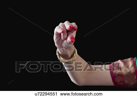 Stock Image - Close-up of a woman's hand making Bharatanatyam gesture called Kangula on black background. Fotosearch