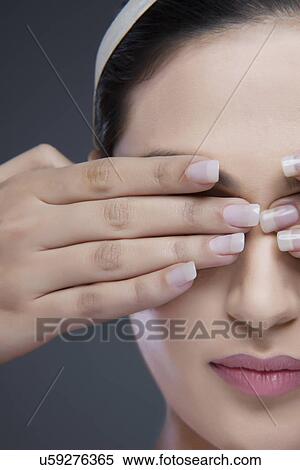 Close-up of a young woman covering eyes with hands over colored background View Large Photo Image Stock Photography - Close-up of a young woman covering eyes with hands over colored background . Fotosearch