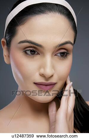 Close-up of an attractive female with hand on face over colored background View Large Photo Image Stock Photo - Close-up of an attractive female with hand on face over colored background . Fotosearch