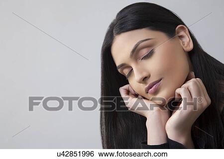 Close-up of an Indian young female with eyes closed over colored background View Large Photo Image Stock Photograph - Close-up of an Indian young female with eyes closed over colored background . Fotosearch