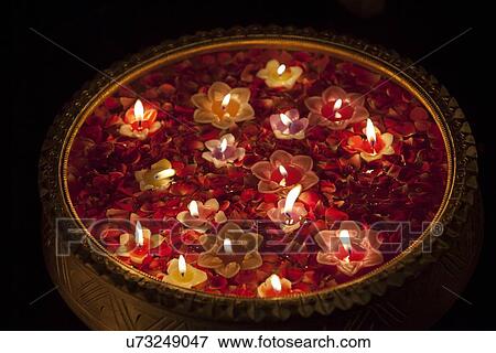 Stock Photo - Close-up of an urn with floating diyas. Fotosearch