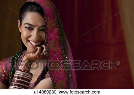 Stock Image - Close-up of beautiful young woman smiling while looking down . Fotosearch