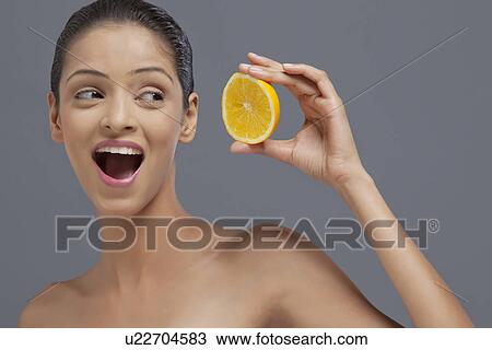 Close-up of beautiful young woman looking at slice of orange View Large Photo Image Stock Image - Close-up of beautiful young woman looking at slice of orange . Fotosearch