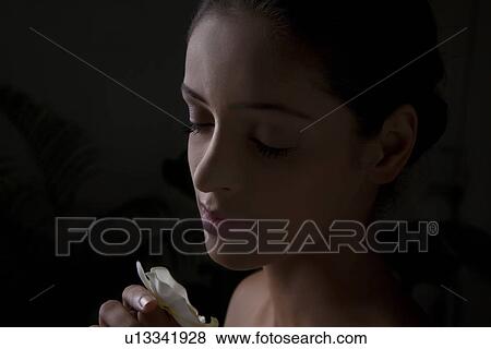 Stock Photo - Close-up of beautiful young woman smelling flower . Fotosearch