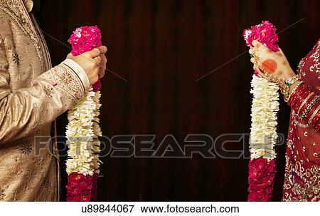 Close-up of bride and groom holding garlands View Large Photo Image Stock Photo - Close-up of bride and groom holding garlands . Fotosearch