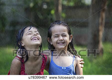 Stock Photo - Close-up of cheerful girls enjoying in rain . Fotosearch