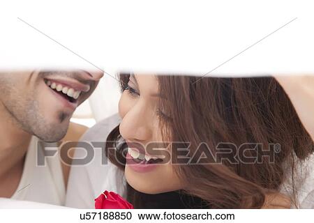 Stock Image - Close-up of couple romancing in bed. Fotosearch