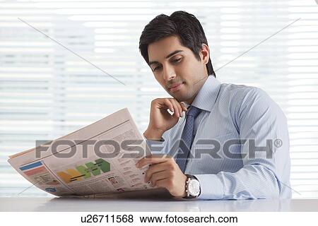 Close-up of handsome young business executive reading world news View Large Photo Image Stock Photo - Close-up of handsome young business executive reading world news . Fotosearch