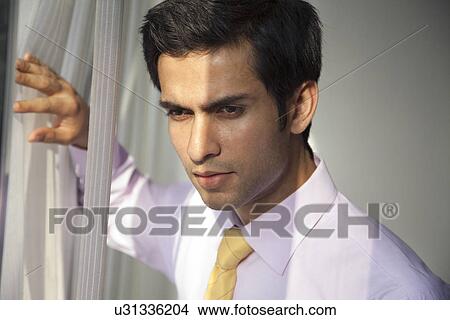 Close-up of handsome young businessman thinking at work View Large Photo Image Picture - Close-up of handsome young businessman thinking at work . Fotosearch