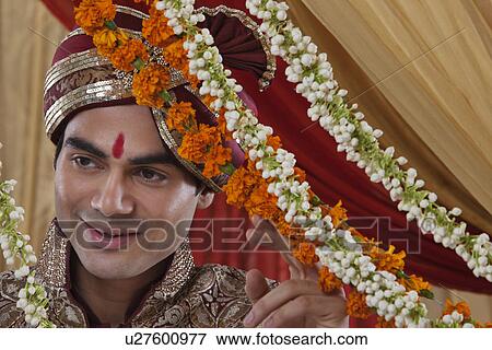 Close-up of happy Indian bridegroom behind wreath looking away View Large Photo Image Stock Photo - Close-up of happy Indian bridegroom behind wreath looking away . Fotosearch