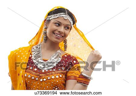 Close-up of happy young woman wearing choli and dupatta over white background View Large Photo Image Picture - Close-up of happy young woman wearing choli and dupatta over white background. Fotosearch