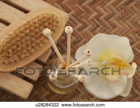 Stock Image - Close-up of reed diffuser with foot brush and orchid . Fotosearch