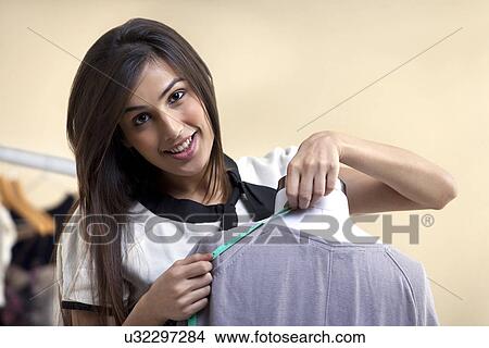 Picture - Close-up of smiling fashion designer measuring length of dress . Fotosearch