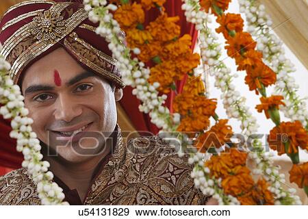 Close-up of smiling young Indian bridegroom behind wreath View Large Photo Image Stock Photo - Close-up of smiling young Indian bridegroom behind wreath . Fotosearch