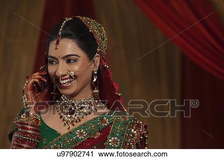Close up of smiling young Indian woman talking on cell phone while looking away View Large Photo Image Stock Image - Close up of smiling young Indian woman talking on cell phone while looking away . Fotosearch