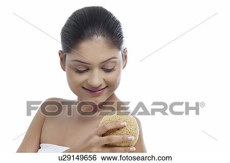 Stock Photograph - Close-up of smiling young woman using massage sponge . Fotosearch