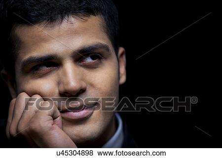 Stock Photo - Close-up of thoughtful business man over black background . Fotosearch