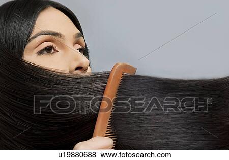 Close-up of woman combing her beautiful long hair over colored background View Large Photo Image Stock Photo - Close-up of woman combing her beautiful long hair over colored background . Fotosearch