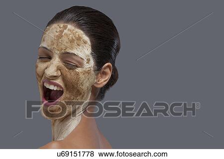 Stock Photo - Close-up of woman with cosmetic mask over colored background . Fotosearch