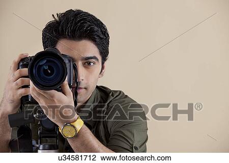 Stock Image - Close-up of young male photographer taking a photograph . Fotosearch