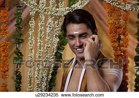 Stock Photography - Close-up of young smiling groom having conversation on cell phone . Fotosearch