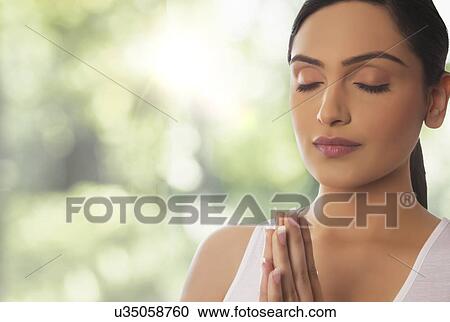 Close-up of young woman meditating against glass window View Large Photo Image Stock Image - Close-up of young woman meditating against glass window. Fotosearch