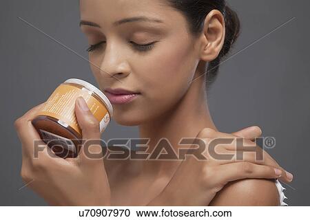 Stock Image - Close-up of young woman smelling scrub bottle . Fotosearch