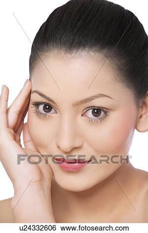 Close-up of young woman smiling while touching her face on white background View Large Photo Image Stock Photograph - Close-up of young woman smiling while touching her face on white background . Fotosearch