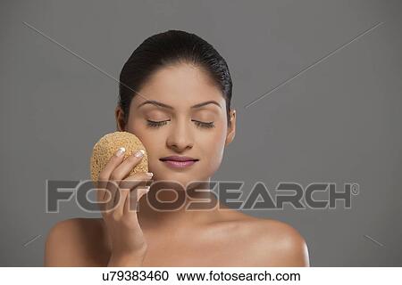 Close-up of young woman using massage sponge over grey background View Large Photo Image Stock Image - Close-up of young woman using massage sponge over grey background . Fotosearch