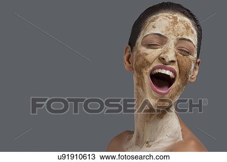 Close-up of young woman with cosmetic mask over colored background View Large Photo Image Stock Image - Close-up of young woman with cosmetic mask over colored background . Fotosearch