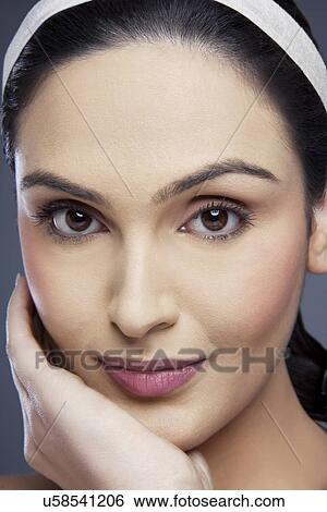 Stock Photograph - Close-up portrait of a beautiful young female smiling over colored background . Fotosearch
