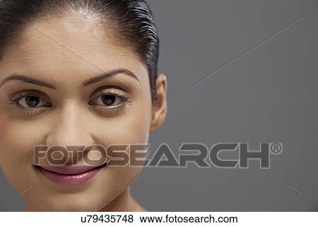 Stock Photo - Close-up portrait of beautiful woman over colored background . Fotosearch
