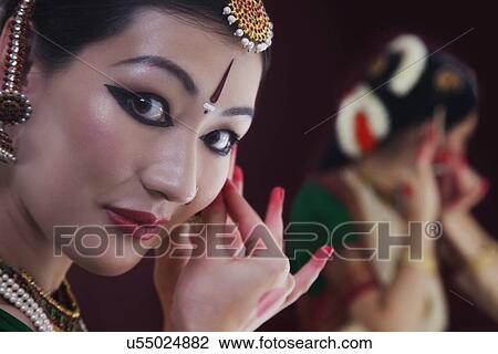 Stock Image - Close-up portrait of Bharatanatyam dancer getting dressed on black background. Fotosearch