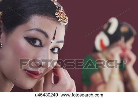 Stock Photo - Close-up portrait of Bharatanatyam dancer getting dressed in front of mirror. Fotosearch