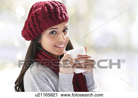 Stock Image - Close-up portrait of young woman holding tea cup . Fotosearch