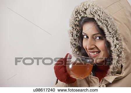 Stock Image - Close-up portrait of young woman smiling while drinking tea . Fotosearch