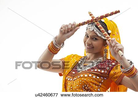 Close-up portrait of young woman holding dandiyas isolated over white background View Large Photo Image Stock Photo - Close-up portrait of young woman holding dandiyas isolated over white background. Fotosearch