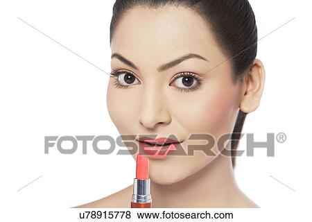 Close-up portrait of young woman applying lipstick View Large Photo Image Stock Photo - Close-up portrait of young woman applying lipstick . Fotosearch