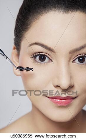 Stock Photography - Close-up portrait of young woman applying mascara . Fotosearch