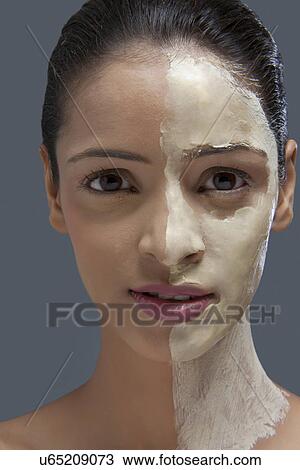 Stock Image - Close-up portrait of young woman with cosmetic mask over colored background . Fotosearch