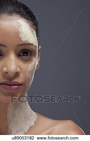 Stock Image - Close-up portrait of young woman with facial mask . Fotosearch